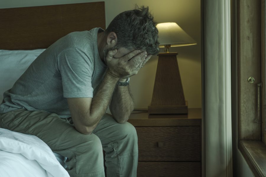 What to Do After Suffering an Injury at a Friend’s Apartment - Attractive depressed and upset man at home bedroom . dramatic lifestyle portrait of 30s to 40s handsome guy sitting sad on bed feeling worried and desperate suffering depression problem