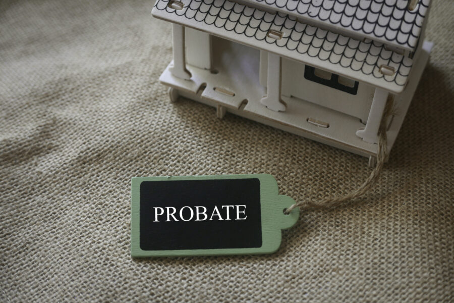 Keep Your Kids From Starting Probate Fights - A toy wooden house on a rugs with a wooden tag written with word Probate.