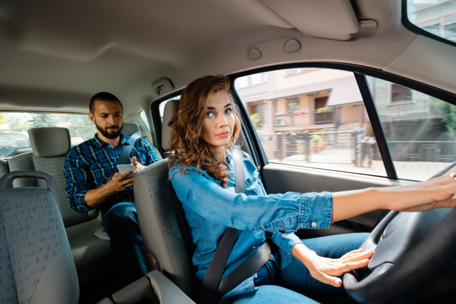 5 Strategies That Promote Safe Driving - Female taxi driver sitting in a car with male passenger